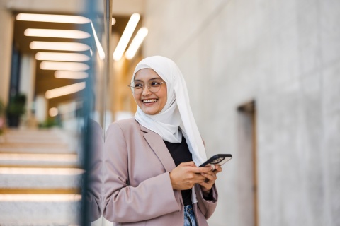 Smiling young woman using smartphone at work