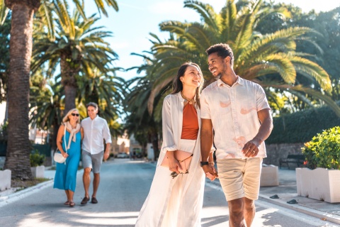 Two couples on holiday in Croatia enjoying a walk along a palm tree-lined promenade