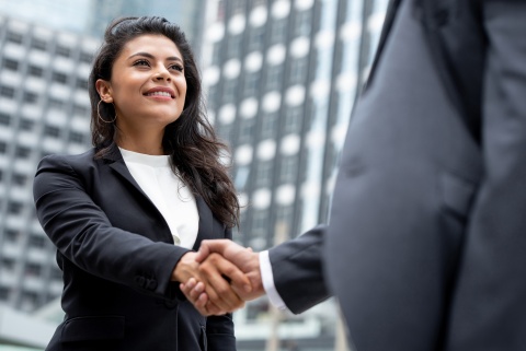 Young smiling businesswoman shaking hands with a partner