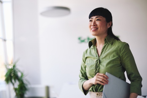 Businesswoman holding a laptop and looking away, smiling