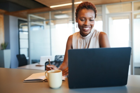 Businesswoman working on a laptop and taking notes in an office