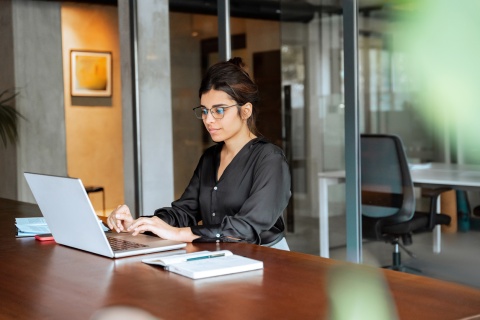 Female graphic designer sitting at desk working on laptop