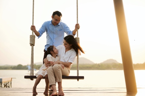 Happy family swinging on dockside swingset in Costa Rica