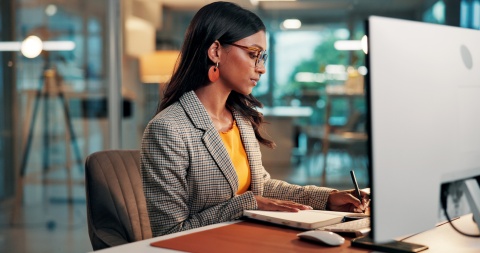 Female paralegal at a law office writing in a notebook at her desk