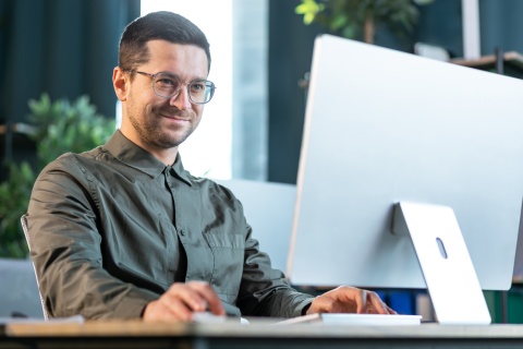 Payroll processor typing on a desktop computer in an office