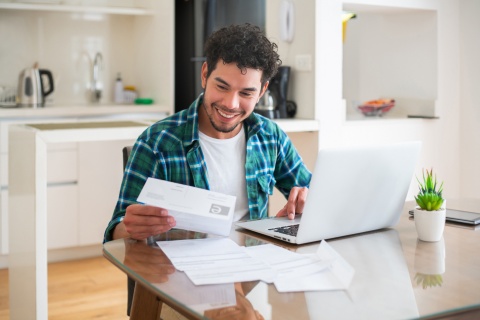 Smiling young man working on his payroll taxes in Kuwait