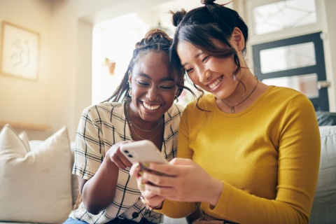 Two women smiling and looking at a phone together