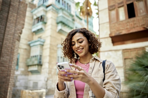 Woman with curly brown hair looking at her smartphone
