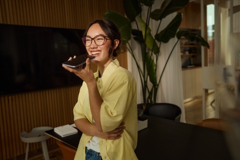 Young businesswoman recording voice message on smartphone