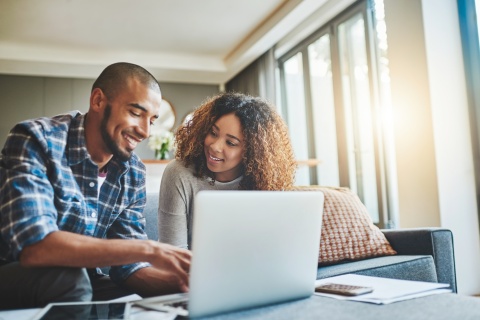 Young couple using a laptop while discussing payroll taxes in Bangladesh