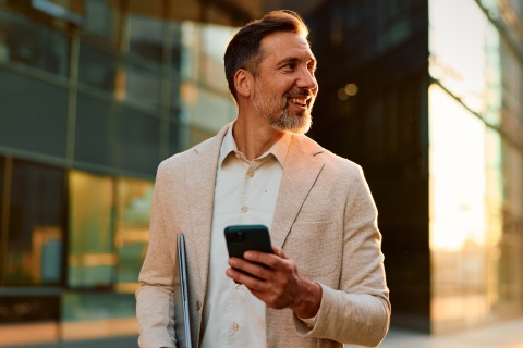 Businessman checking business expenses on his phone while stepping out of the office.