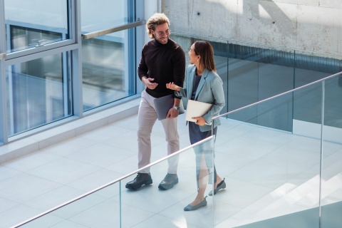 Coworkers chatting while walking through an office, reflecting internal mobility.