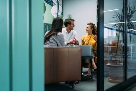 Coworkers in a casual office meeting, discussing variable compensation.