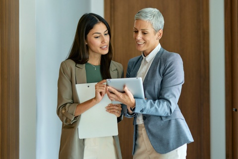 Two colleagues reviewing a 30-60-90 day plan on a tablet.